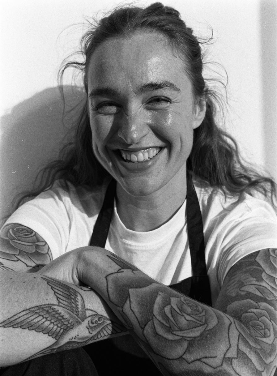 Sofie, laughing, with a rose and a swallow on her forearms