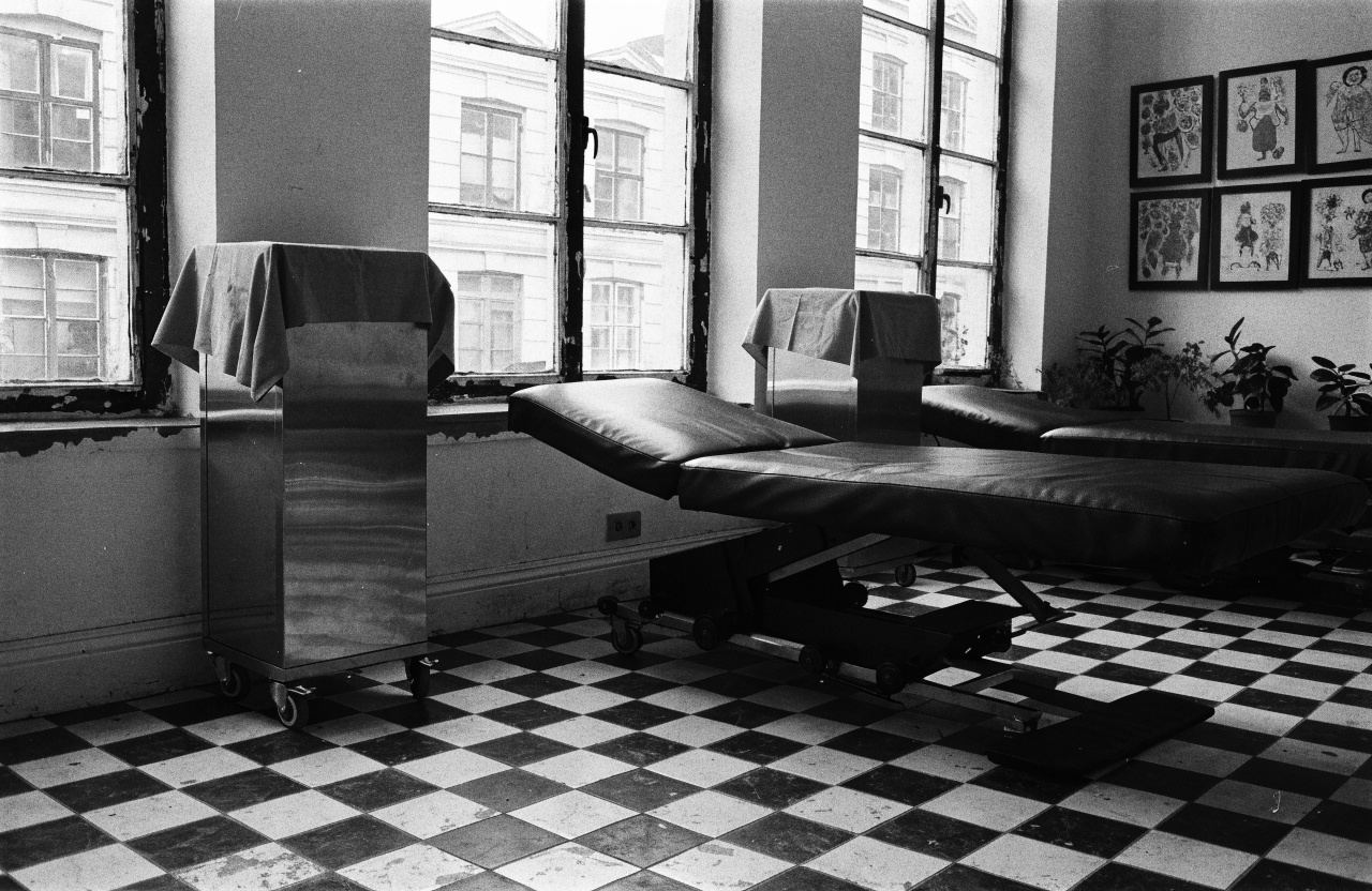 The studio room: black tattoo beds on a chequered floor, flash on the walls
