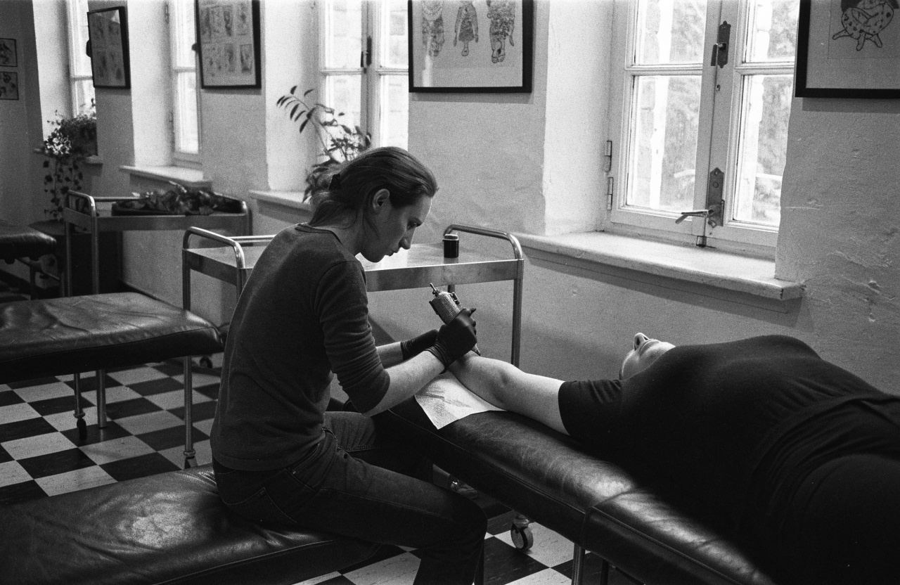 An artist at work on a client lying on a tattoo bed